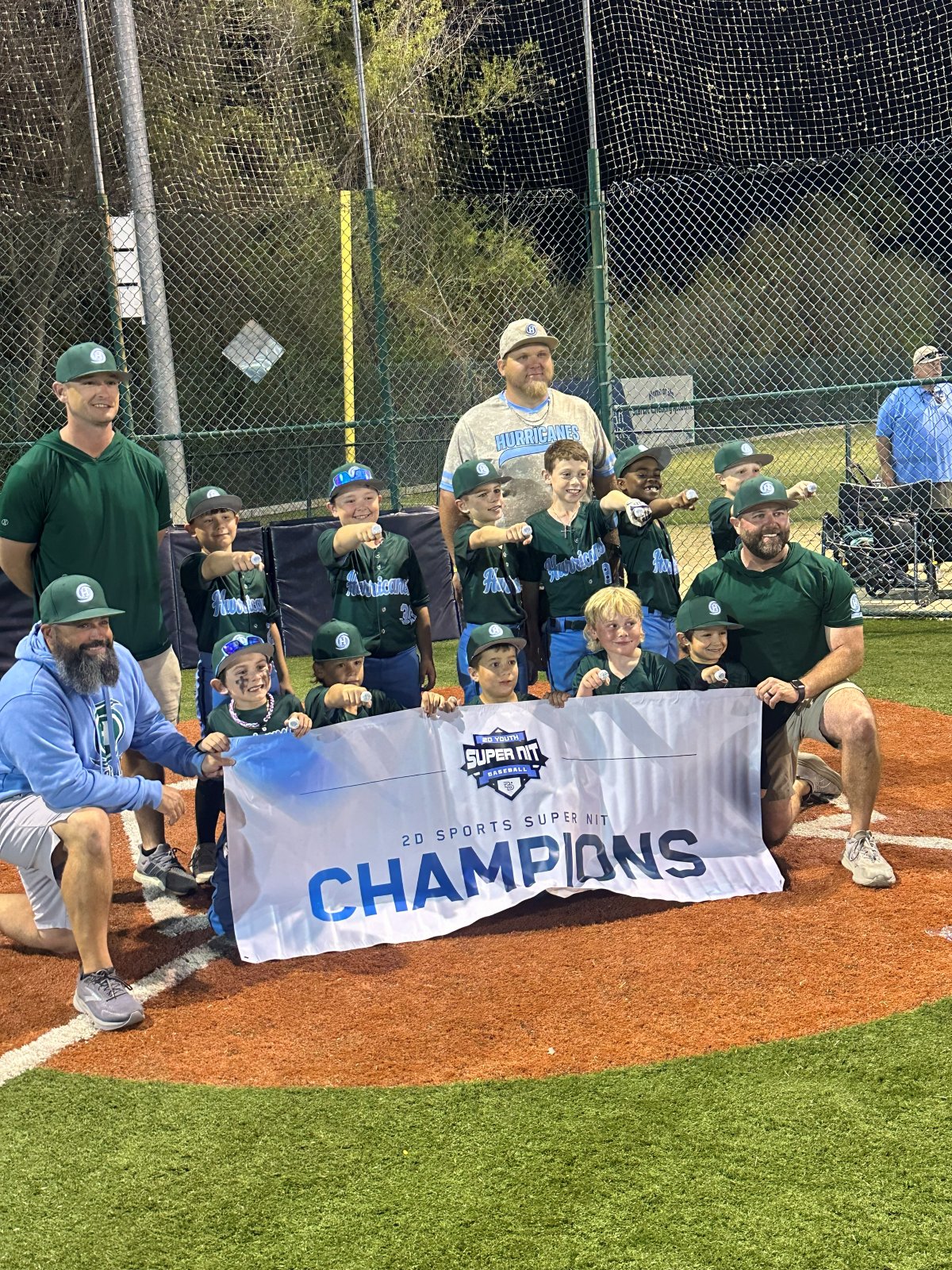 Hurricanes team and coaches with a Champions banner