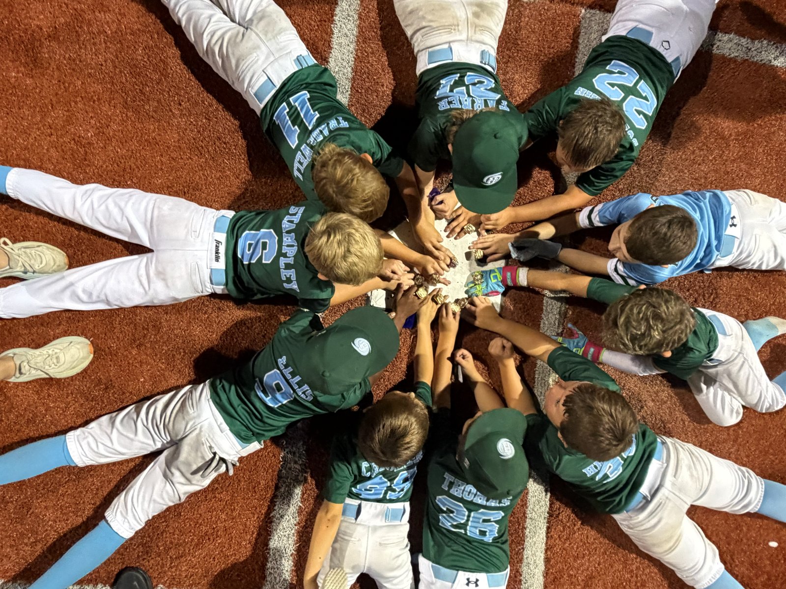 Hurricanes players lying in a circle around home plate with their championship rings